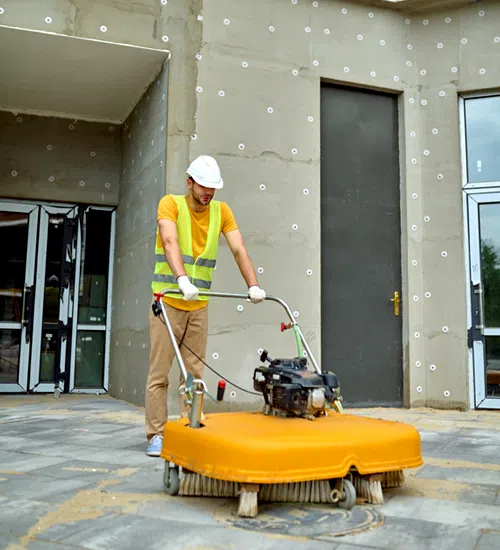 Cleaner operating a floor-cleaning machine at a building site